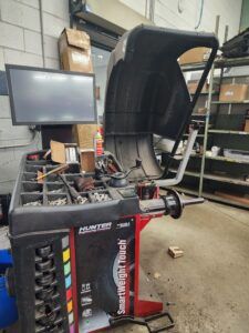 Hunter wheel balancer in a garage, with a computer screen and assorted tools.