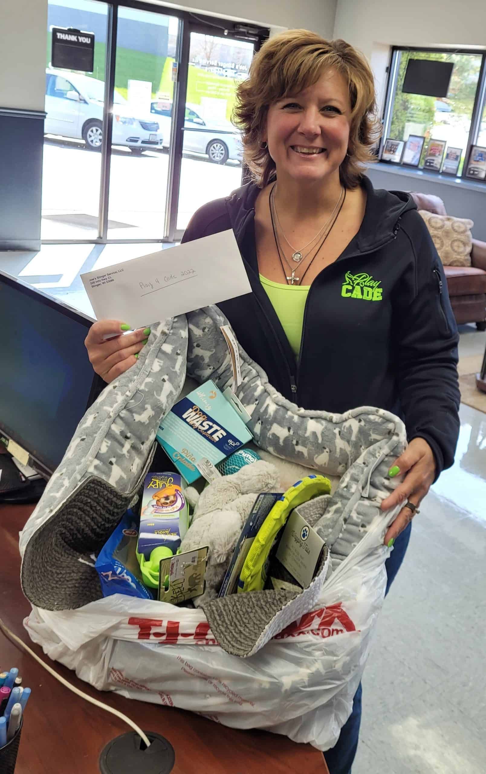 Woman holding a bag of items, smiling. Holding an envelope. Interior shot.