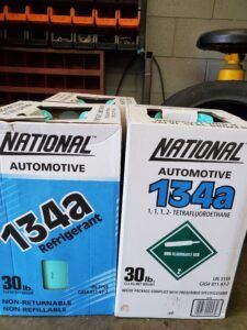 Two boxes of National Automotive 134a refrigerant. One blue, one white, each labeled