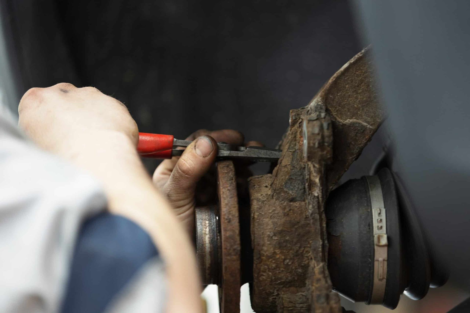 Person using pliers to work on a rusted car wheel.