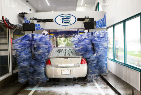 Car in an automated car wash with blue spinning brushes and water spraying around it
