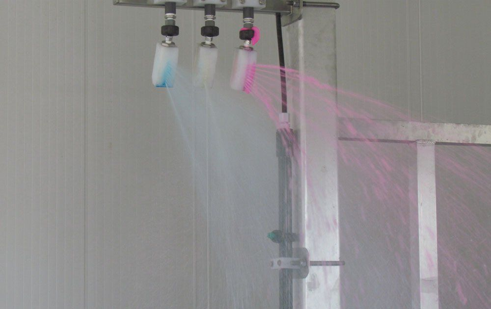 A row of brushes spraying water in a room.