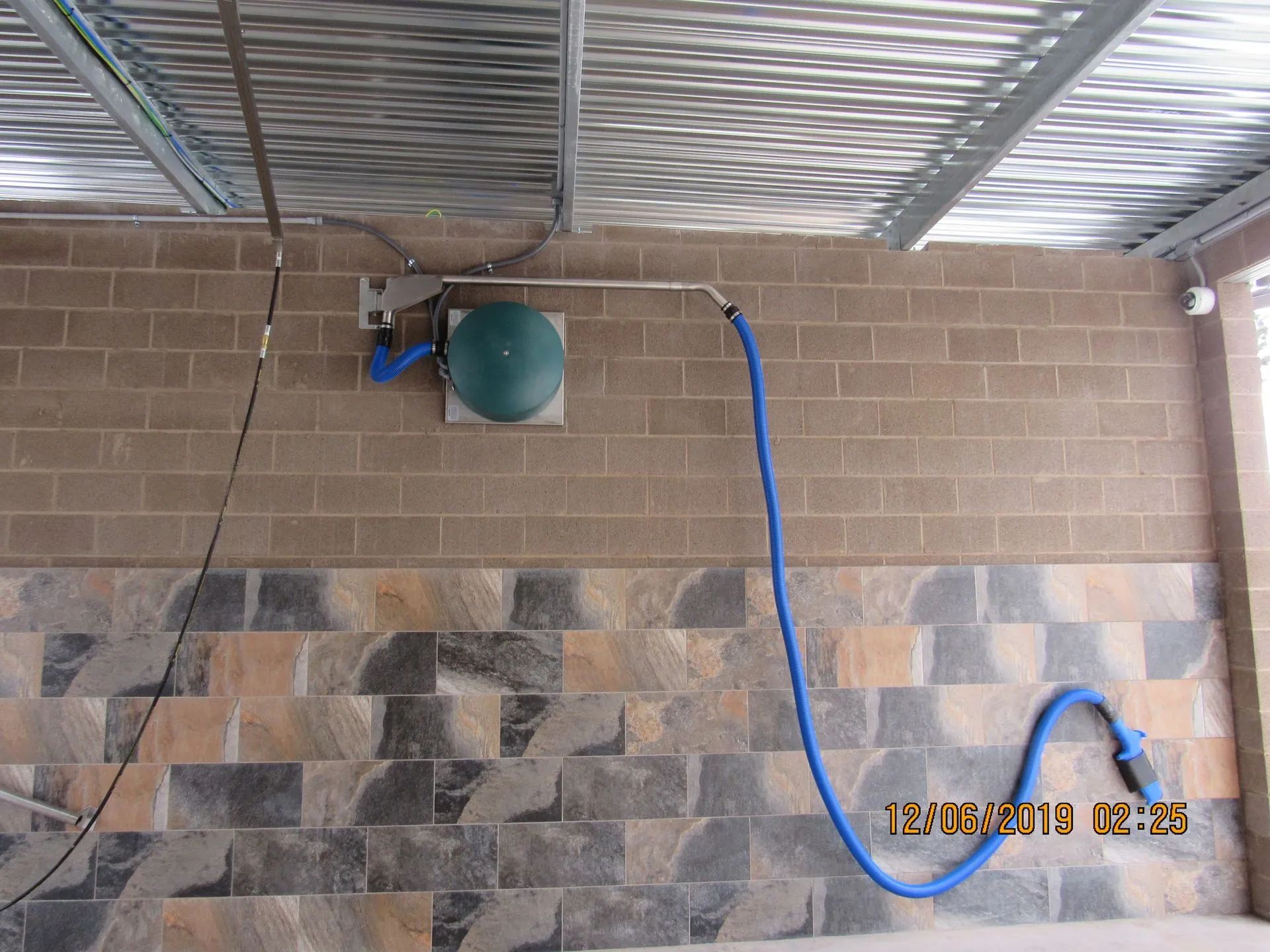 A blue hose is attached to a brick wall