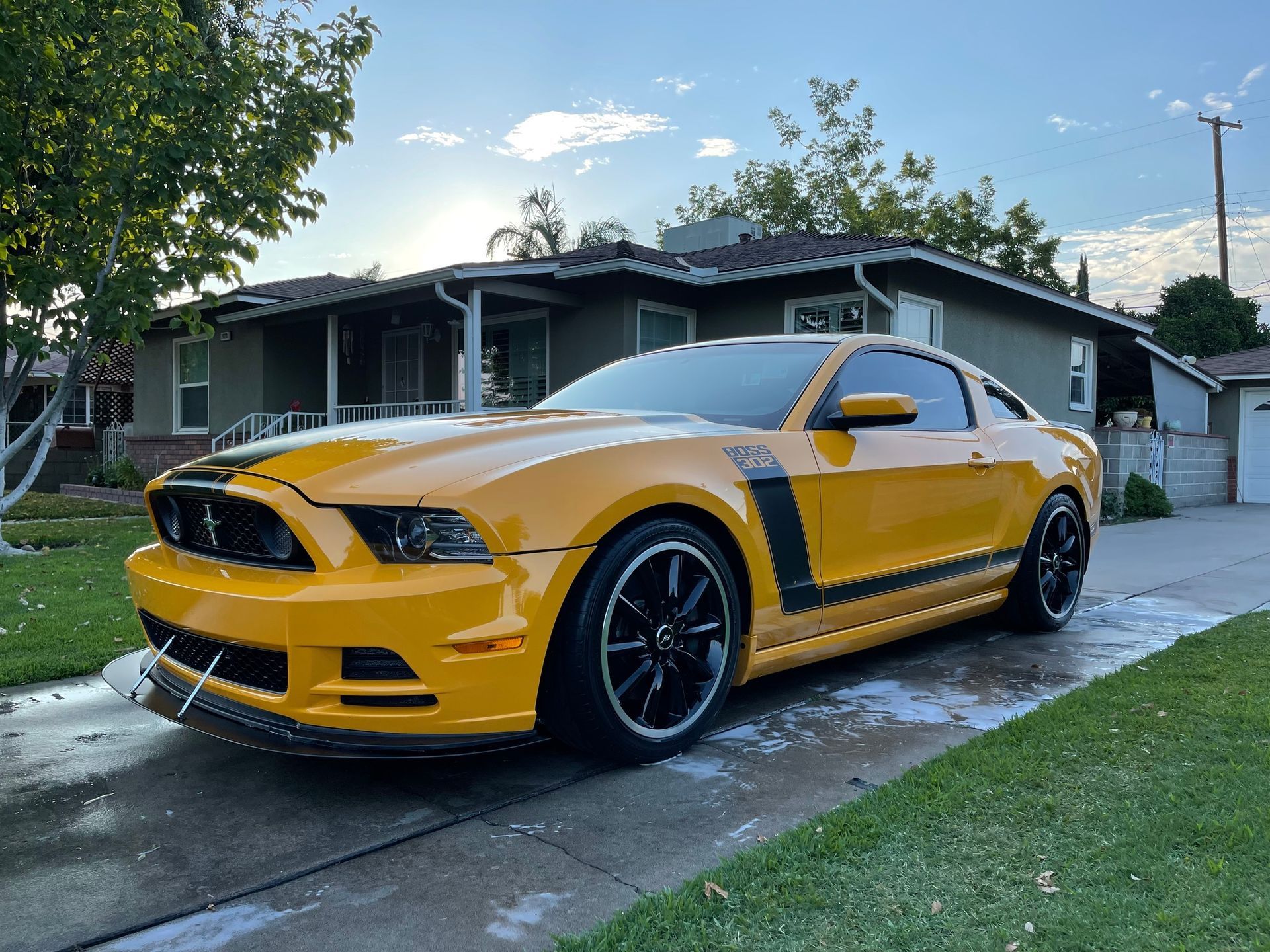 A yellow mustang is parked in front of a house.