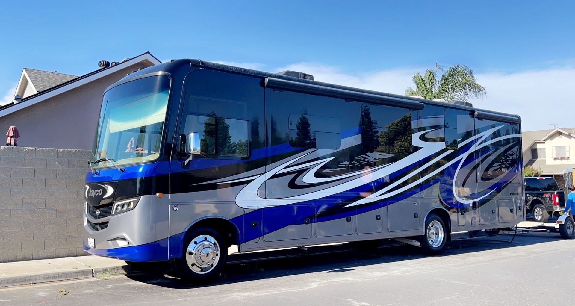 A large blue and gray rv is parked on the side of the road.
