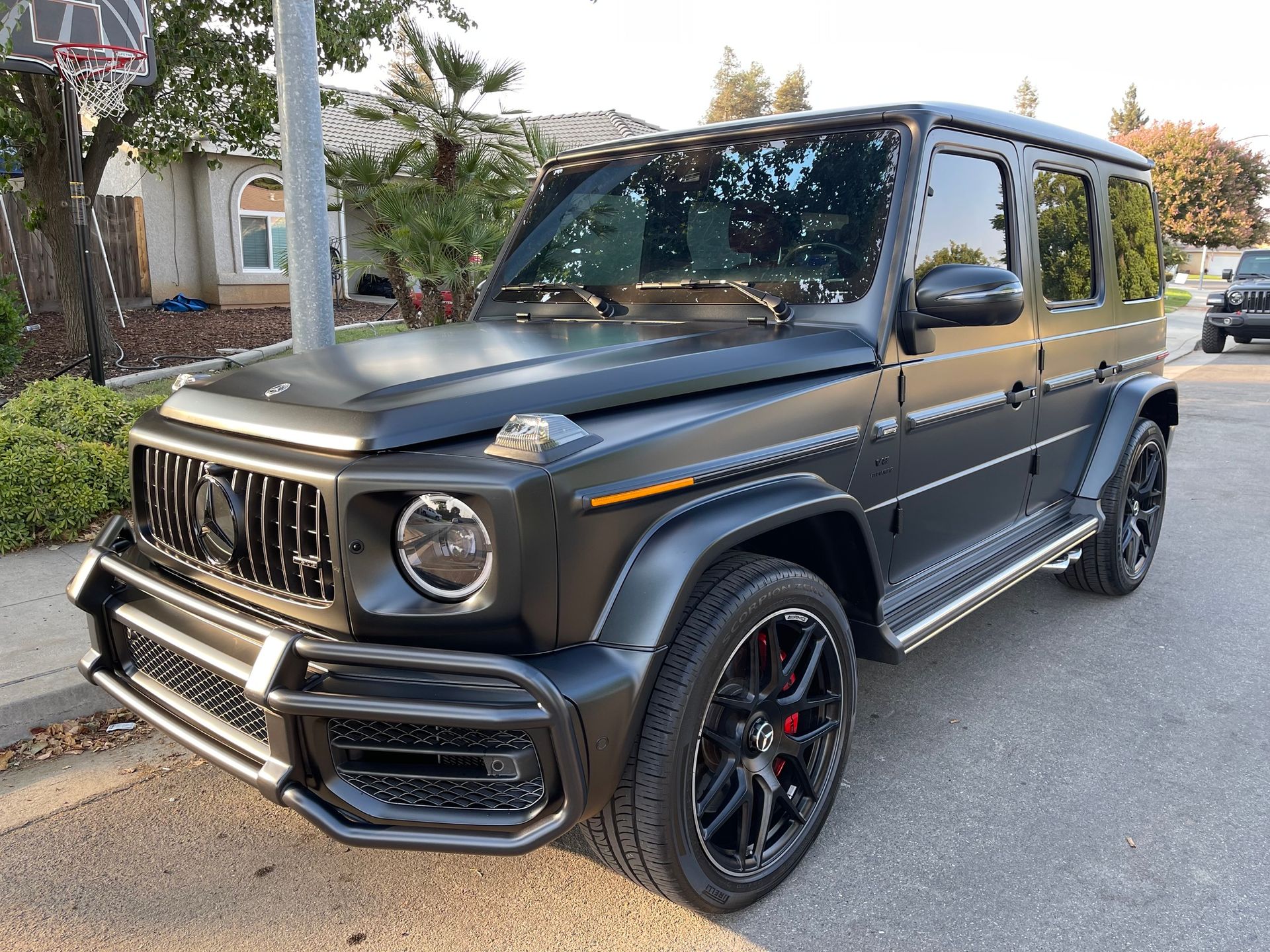 A black mercedes benz g63 amg is parked on the side of the road.