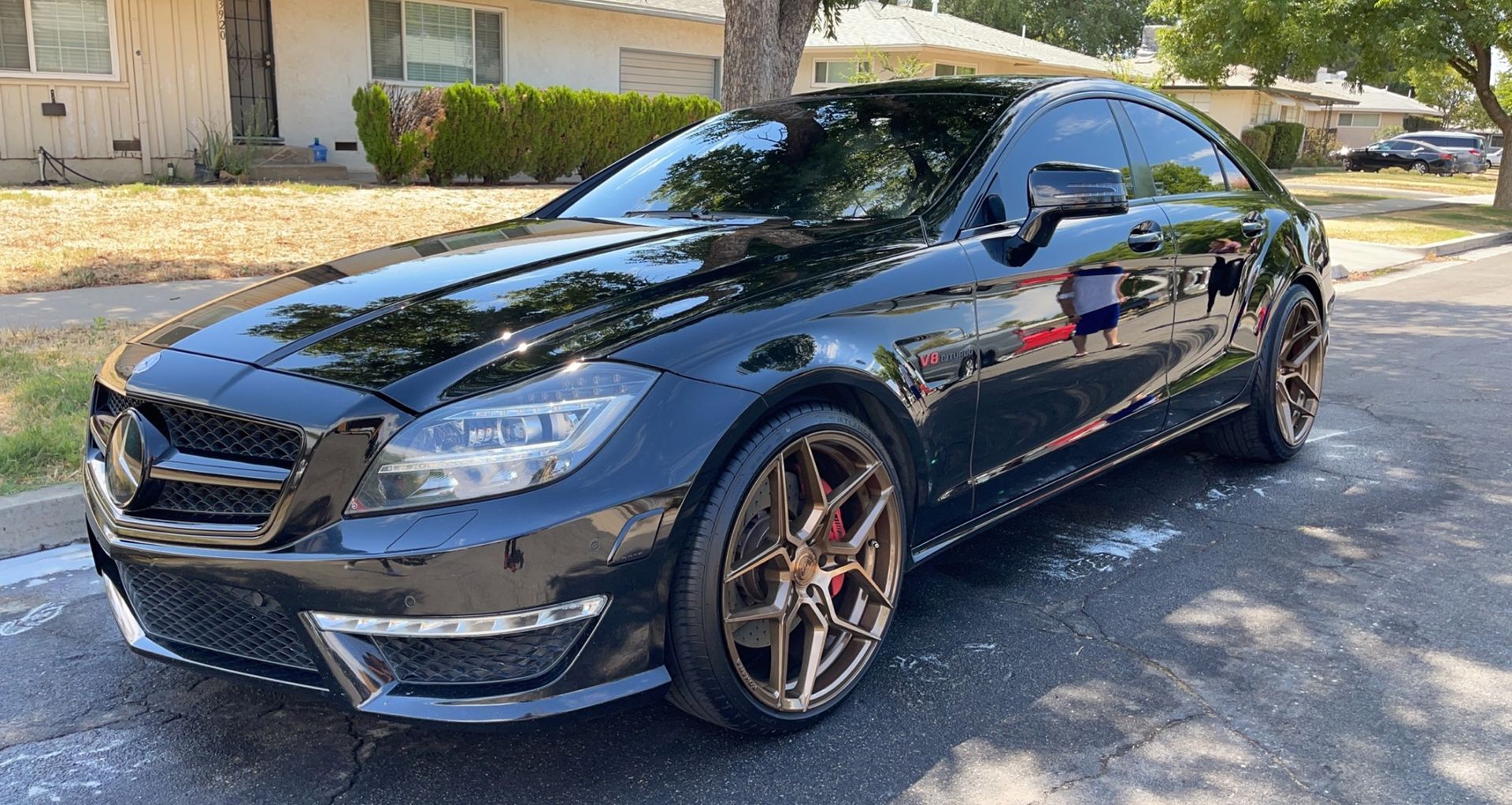 A black mercedes benz cls 63 amg is parked on the side of the road.