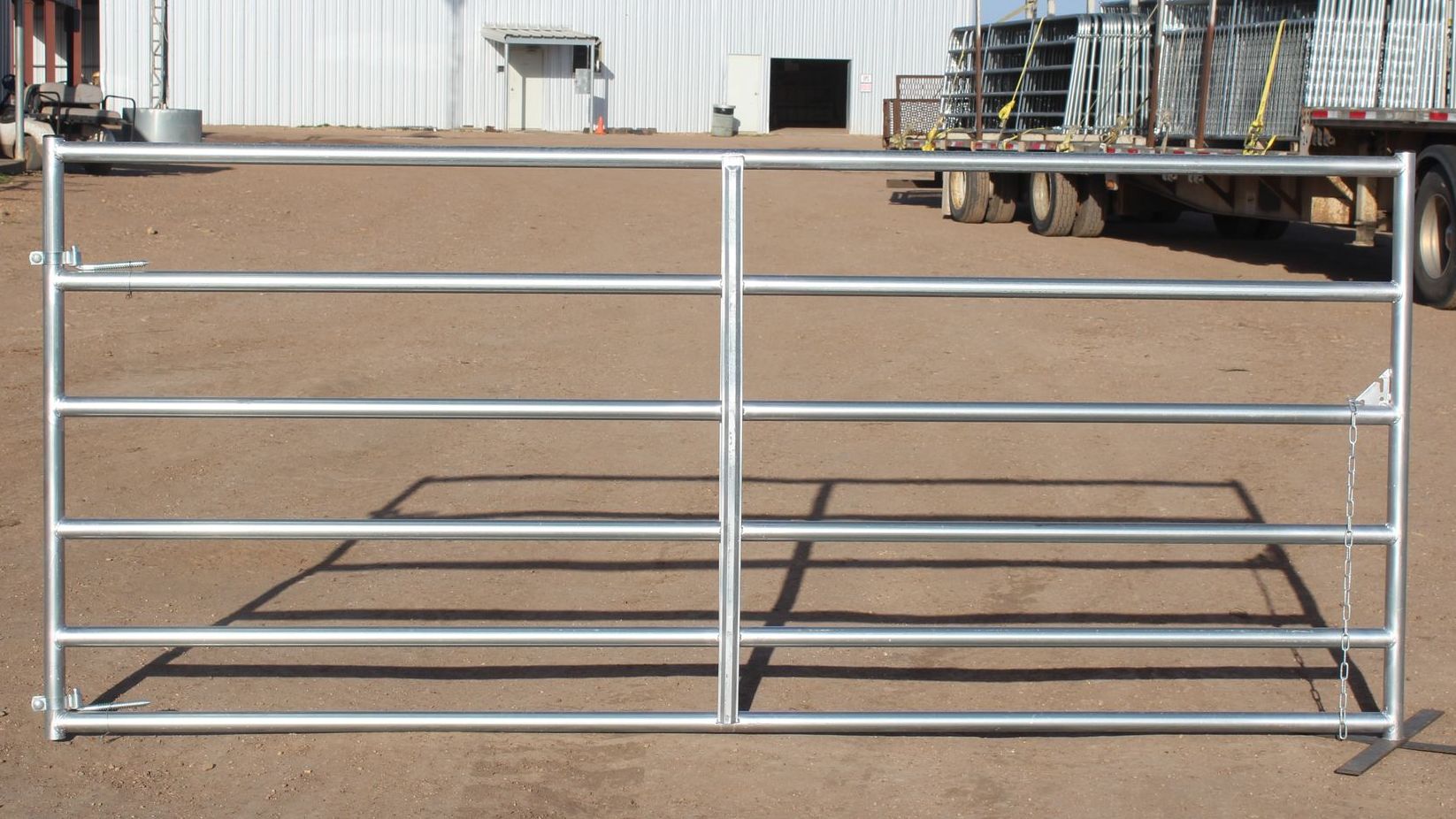 A metal gate is sitting in the dirt in front of a building