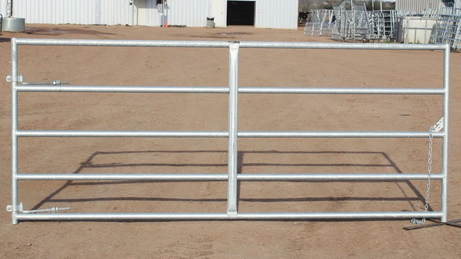 A metal gate is sitting in the dirt in front of a building