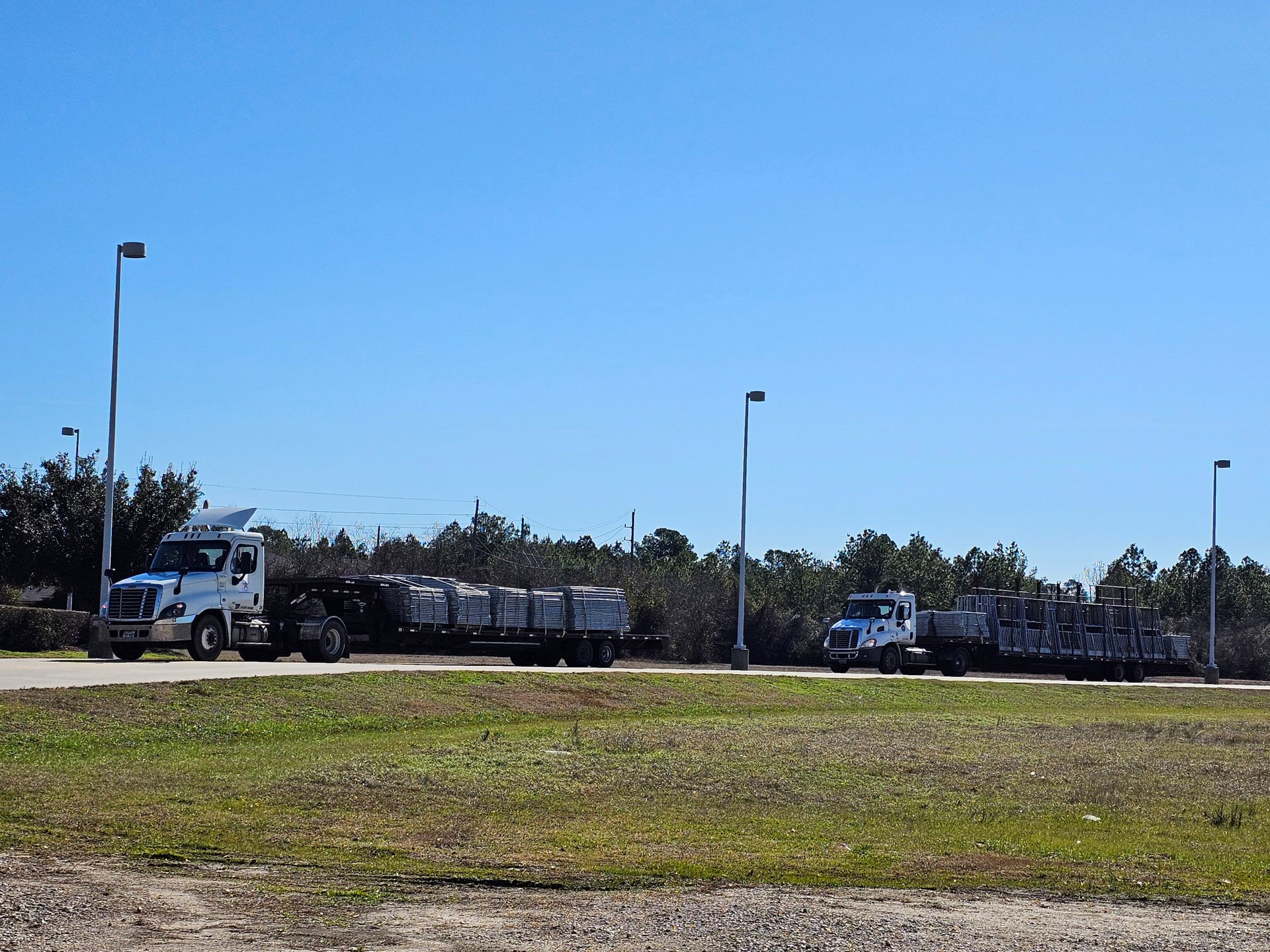 A row of semi trucks are driving down a road.
