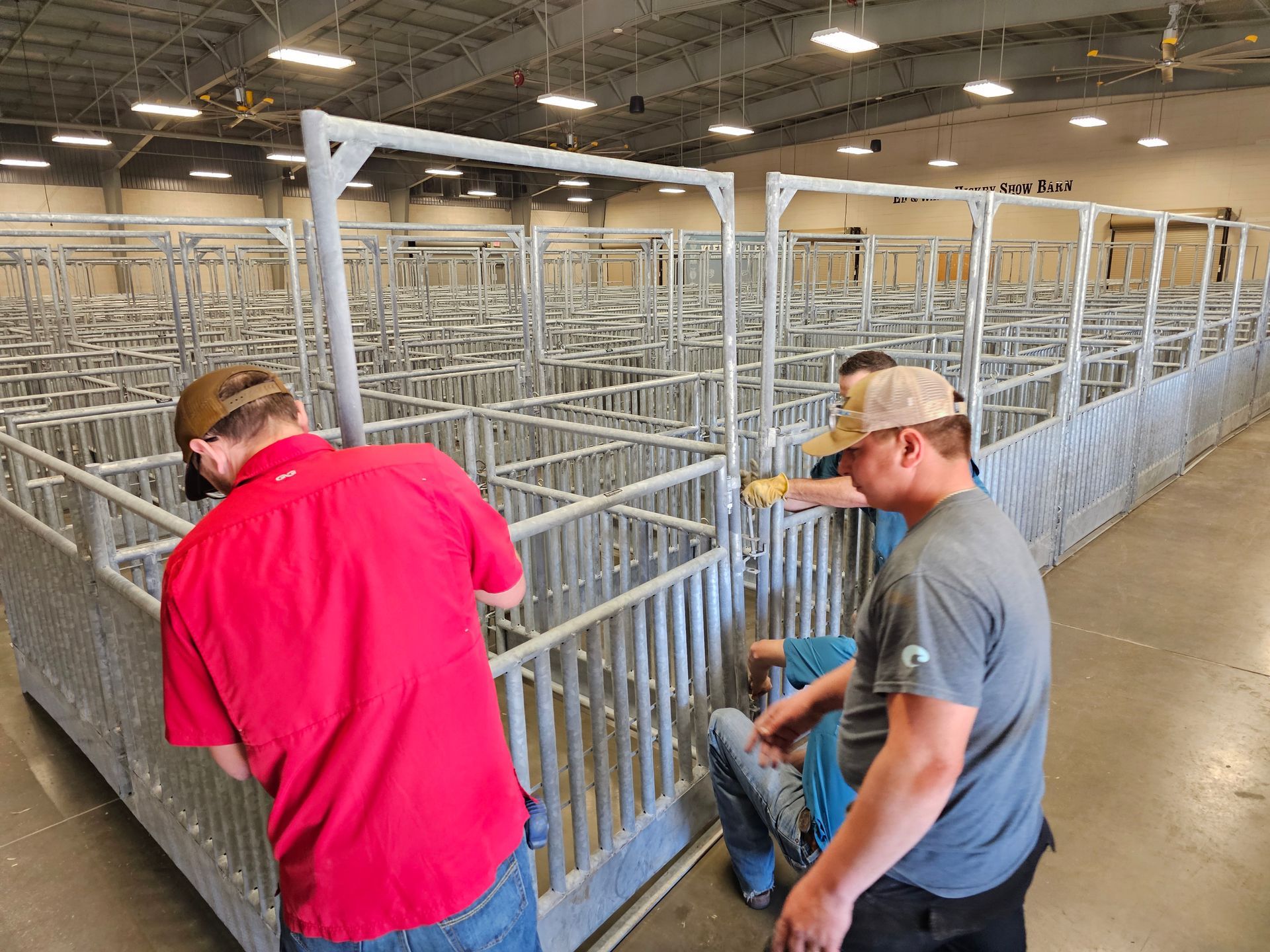 A group of men are working on a fence in a warehouse.