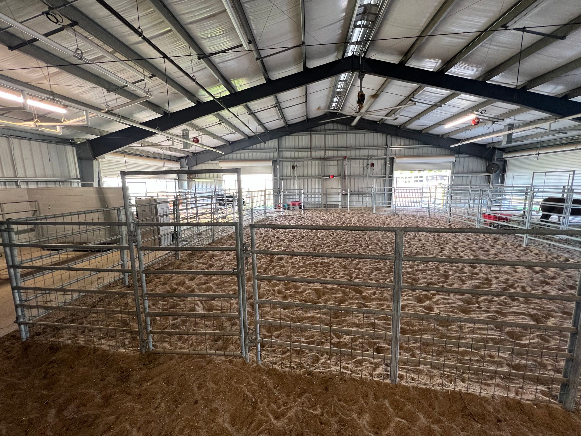 A large indoor arena with a fence and a lot of dirt.