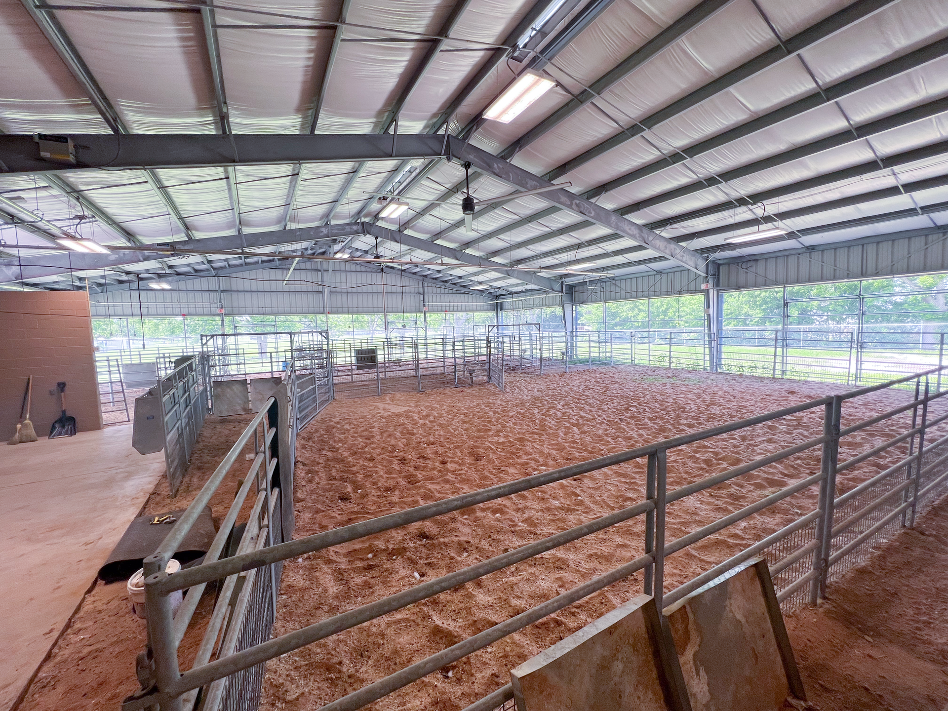 A large indoor arena filled with dirt and a fence.