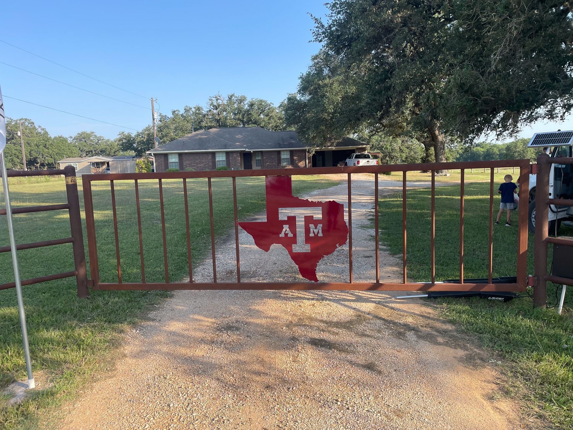 A gate with a texas flag on it is in front of a house.