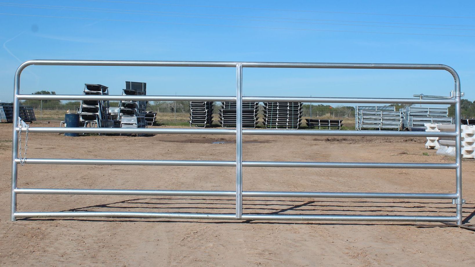A galvanized gate is sitting in the middle of a dirt field