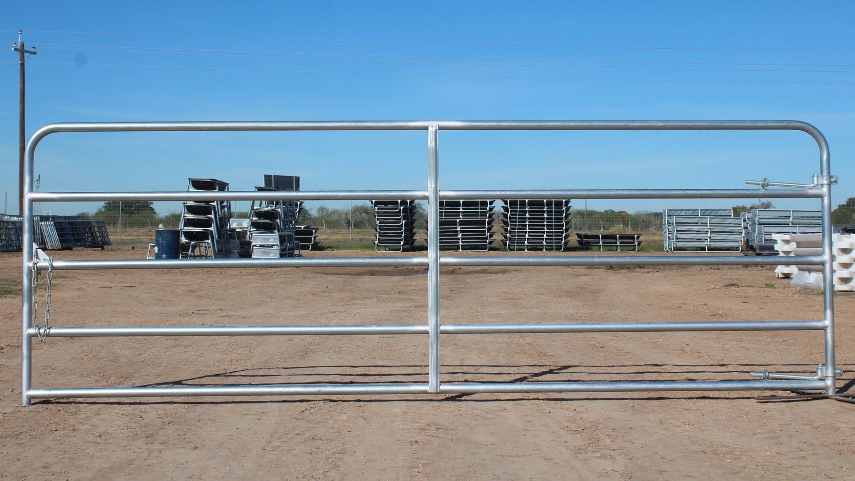 A metal gate is sitting in the middle of a dirt field.