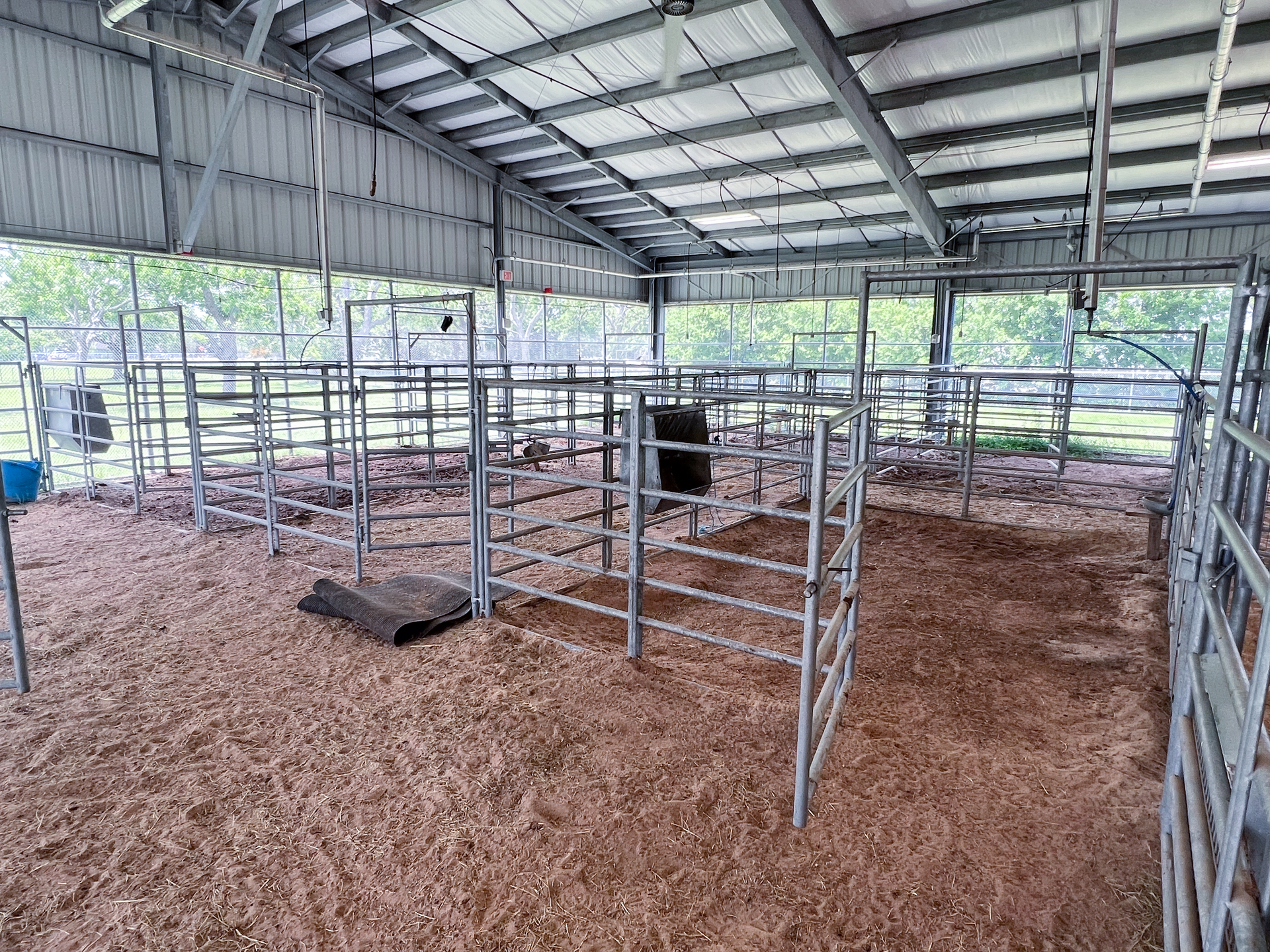 A barn with a lot of fences and a lot of dirt in it.