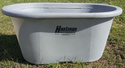A large gray tub is sitting in the grass.