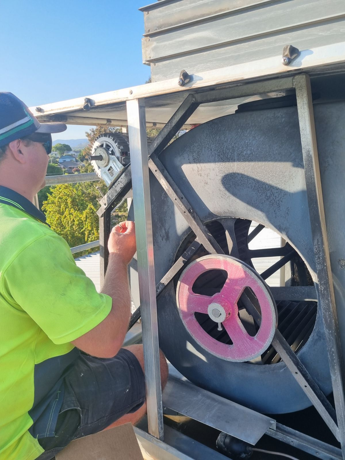 Worker in neon shirt inspecting a large pink valve on industrial equipment outdoors. - Care Mechanical Services in Wagga Wagga, NSW