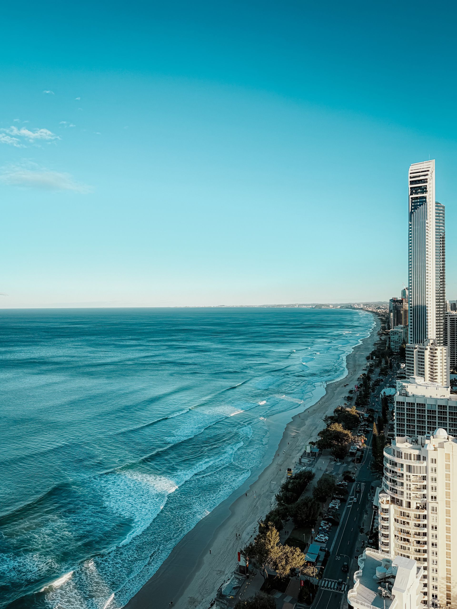 Ocean view of a city with skyscrapers, beach, blue sky, and turquoise water.