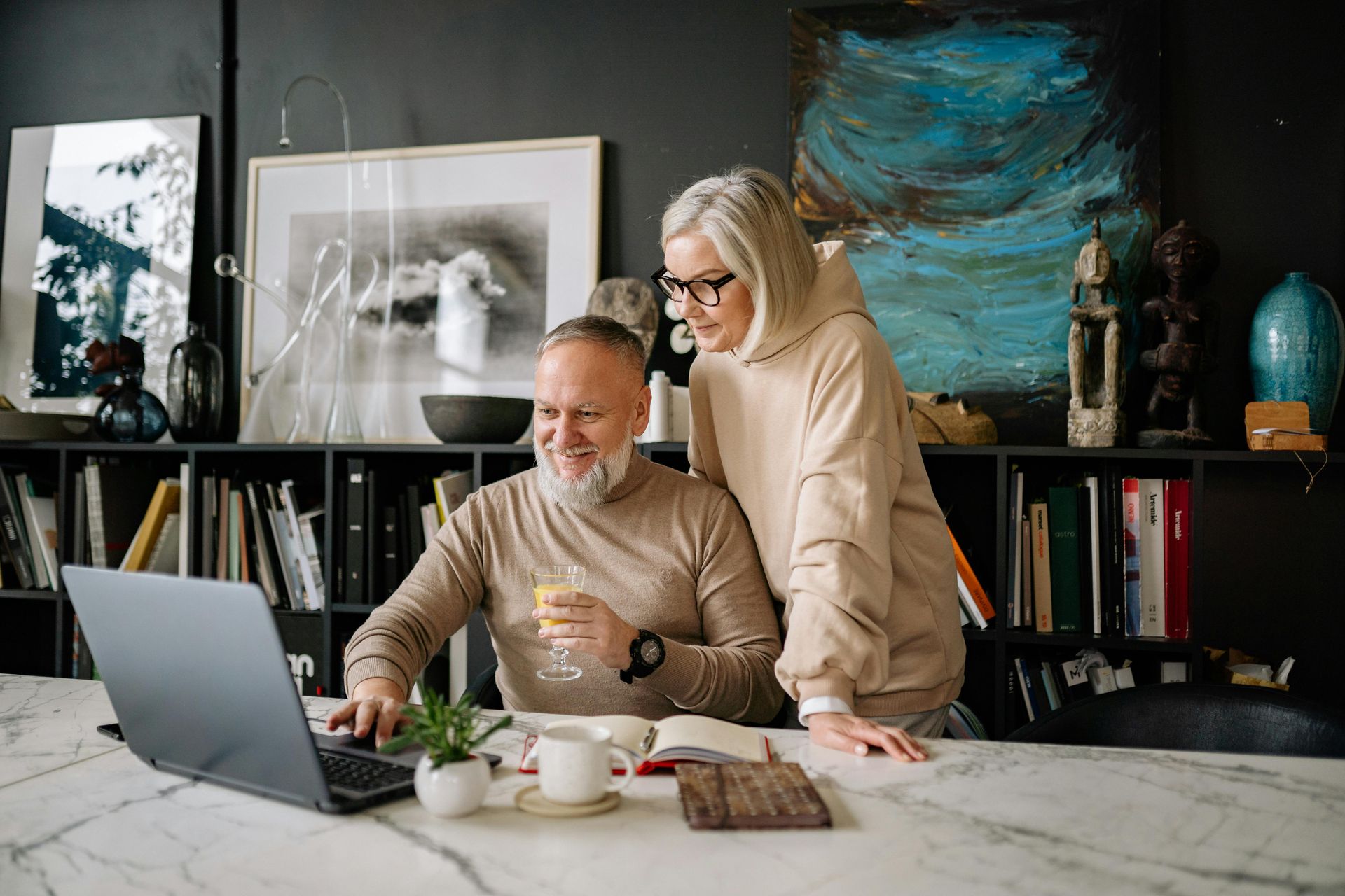 Two people reviewing documents at a desk with a laptop in a modern home office.