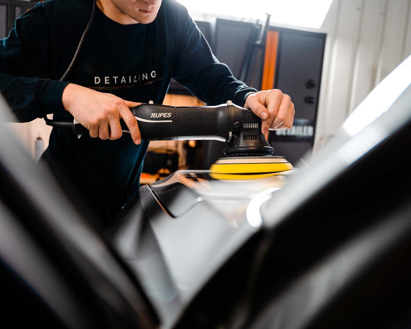 A man is polishing a car with a machine.