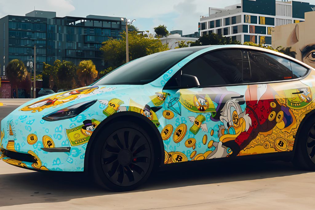 A Tesla Model Y featuring a vibrant custom graphic wrap inspired by comic art, including bold illustrations of Scrooge McDuck, dollar bills, and Bitcoin symbols on a bright blue background. The design exudes personality and creativity.