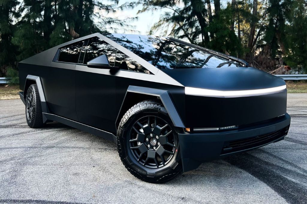 Black Tesla Cybertruck parked on asphalt, with visible wheels and geometric design, outdoors.