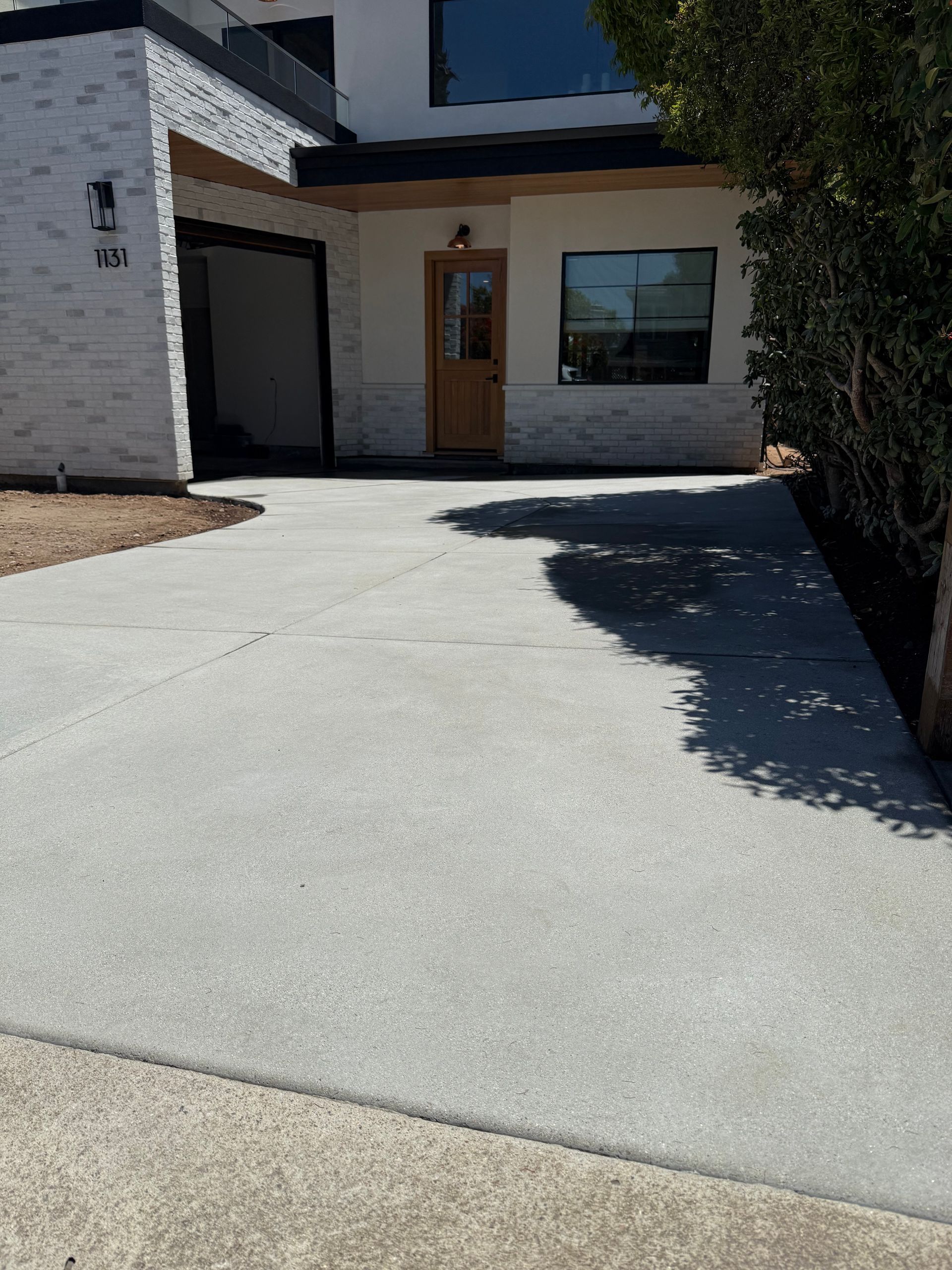 Modern house exterior with a wide concrete driveway and shaded front entrance