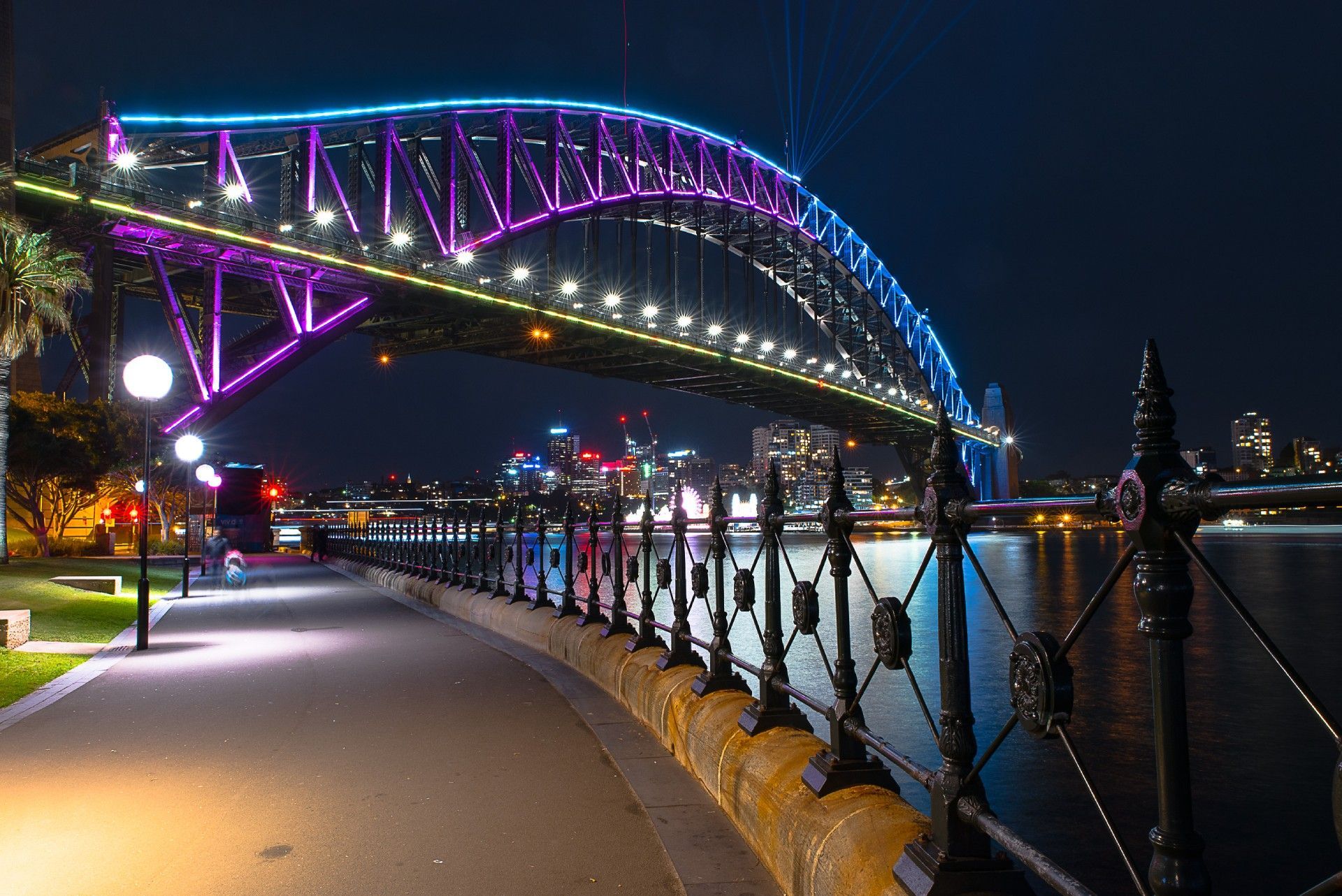 A bridge over a body of water is lit up at night.