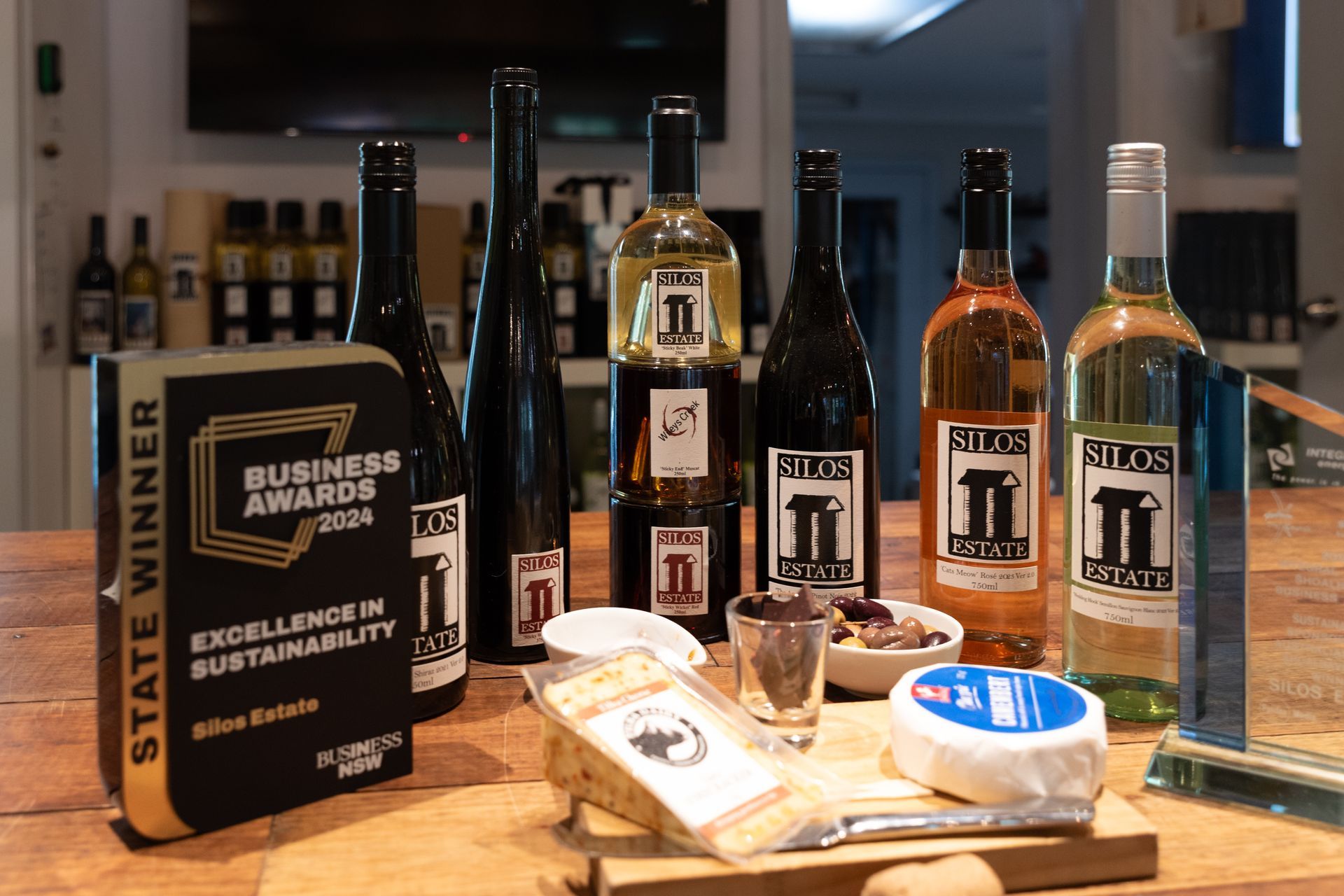 A wooden table topped with bottles of wine and cheese.