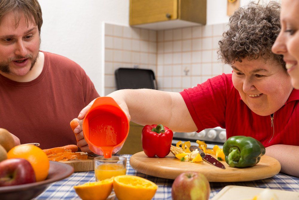A Mentally Disabled Woman And Two Caretakers Cooking Together — iCan Support Services Kawana QLD