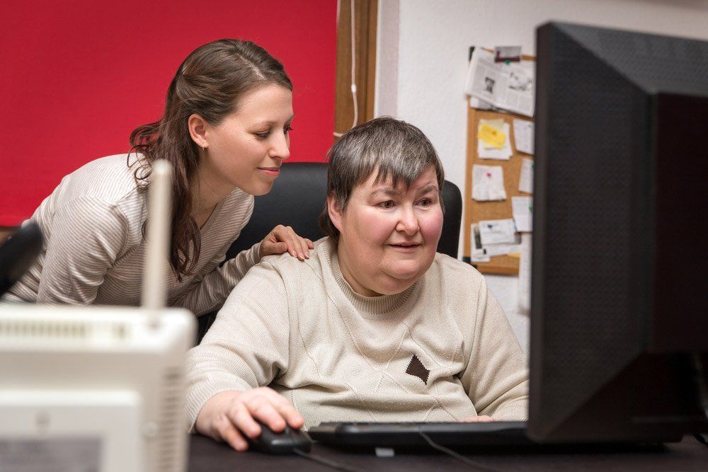 Caregiver And Mentally Disabled Woman Learning At The Computer Special Education — iCan Support Services Kawana QLD
