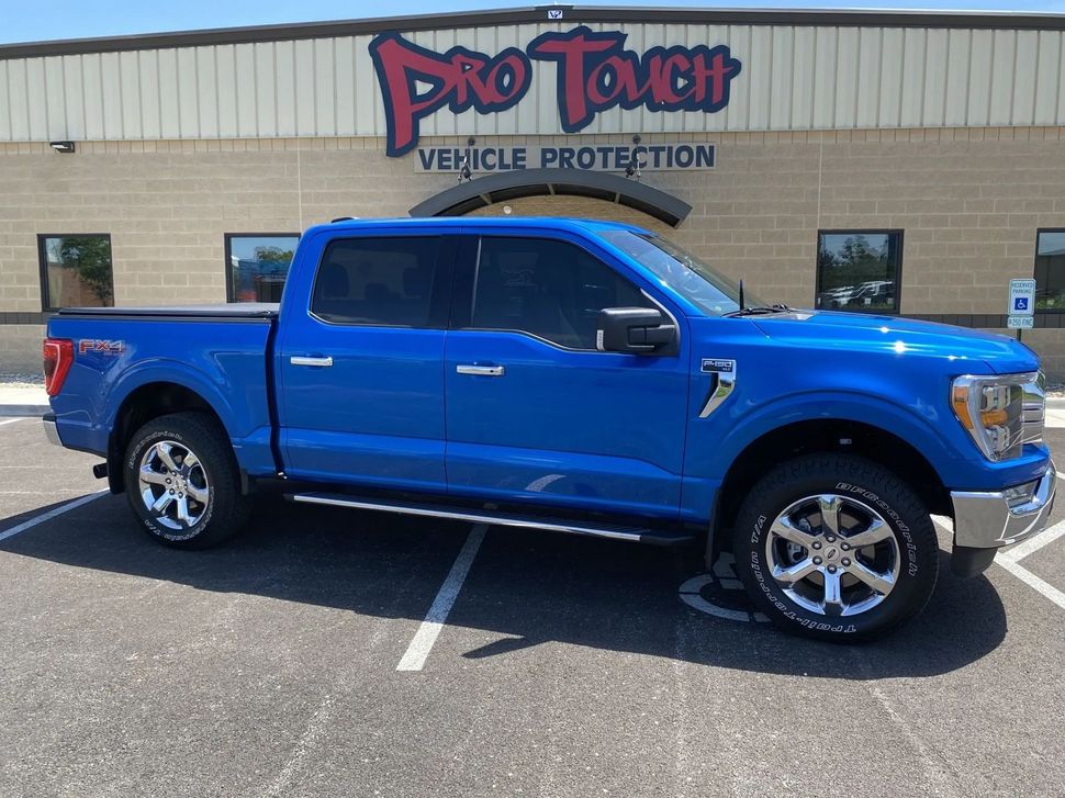 Blue Ford F-150 truck parked in front of Pro Touch Vehicle Protection building on a sunny day.