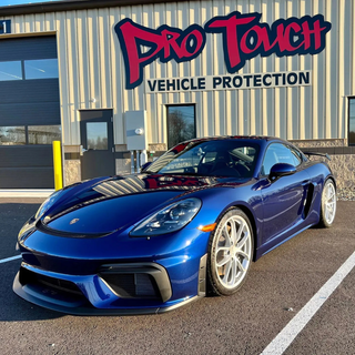 Blue Porsche sports car parked in front of Pro Touch Vehicle Protection building.