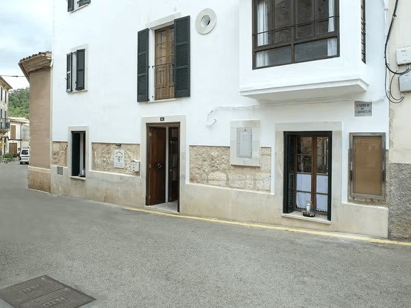 White building on a street corner with open door and windows. Gray pavement.