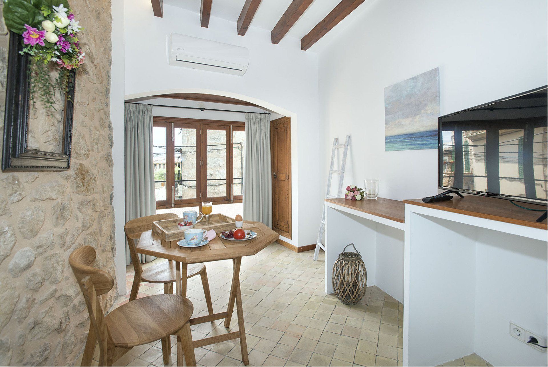 Cozy dining area with wooden table, chairs, and stone walls. Open door leads to exterior.