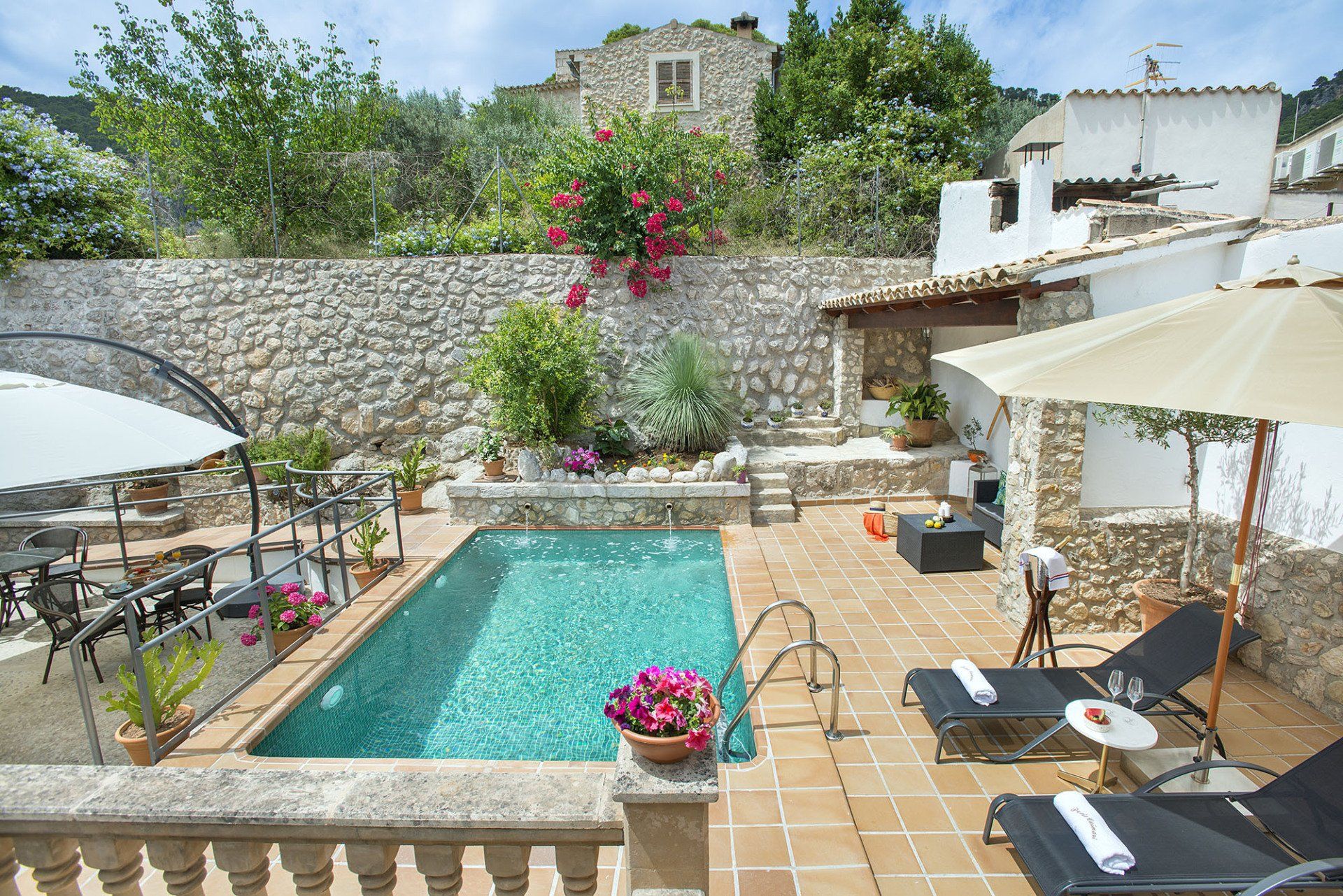 Swimming pool with sun loungers, parasols, and seating area in a Mediterranean courtyard.