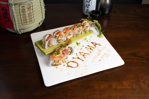 A white plate topped with sushi (Oyama Special Roll) on a wooden table.