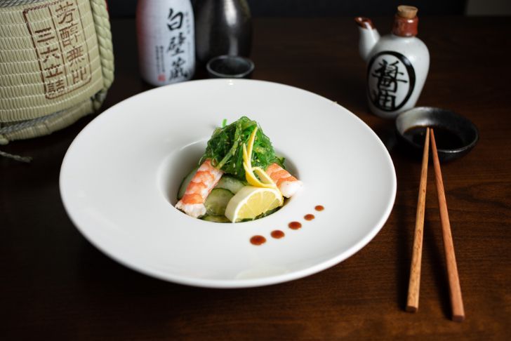 A plate of food with chopsticks on a wooden table.