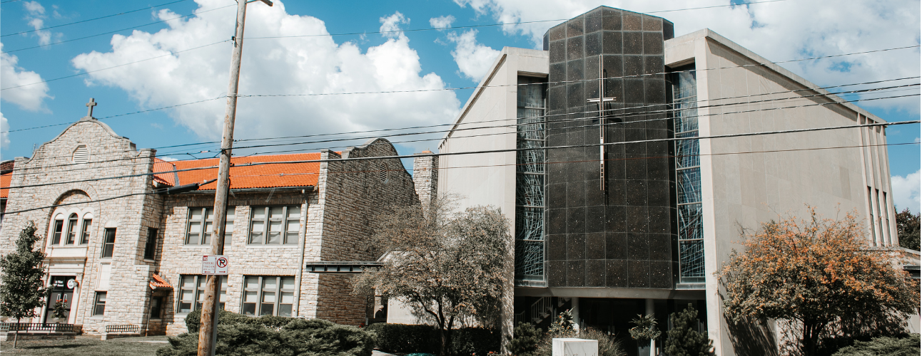 A large building with a cross on top of it is surrounded by smaller buildings.