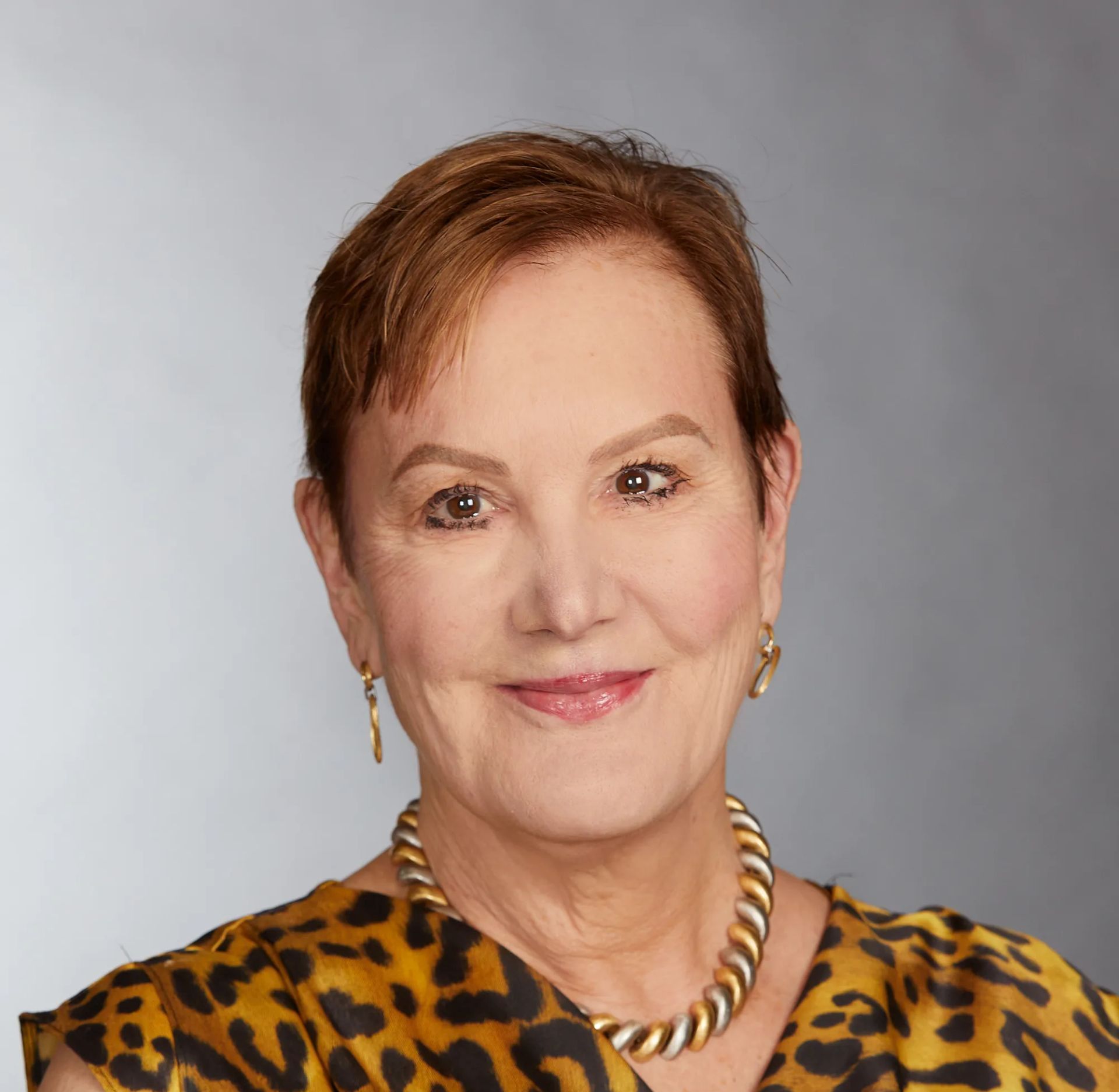 A woman wearing a leopard print top and a gold necklace