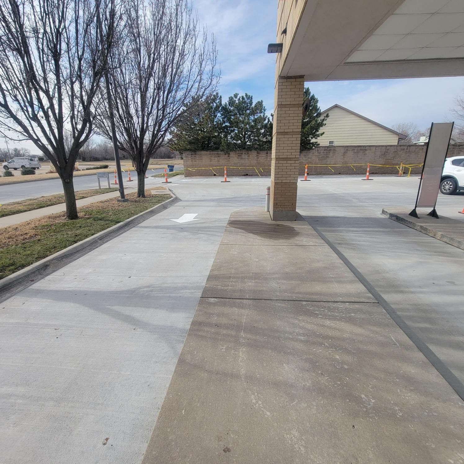 A parking lot with a white car parked in front of a building