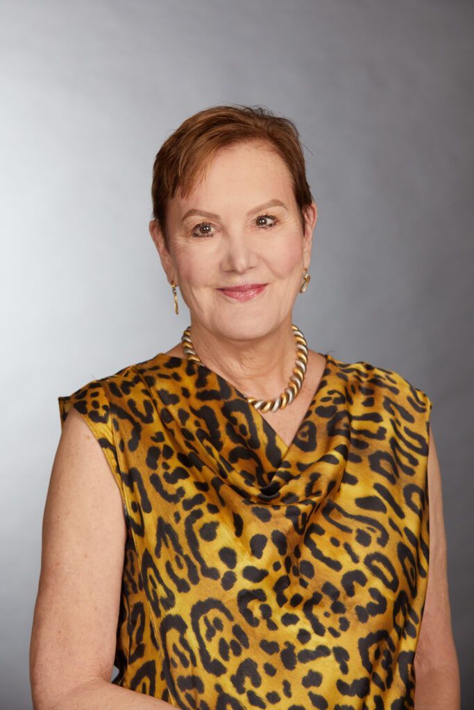 A woman is wearing a leopard print top and a necklace.