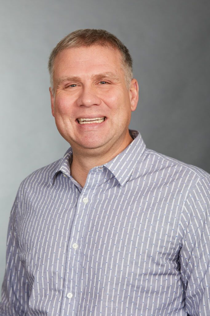 A man in a striped shirt is smiling for the camera.