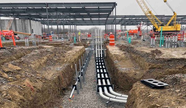 A construction site with a lot of pipes in the dirt.