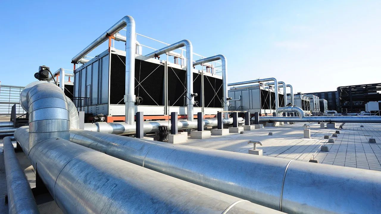 A row of pipes going through a factory with a blue sky in the background.