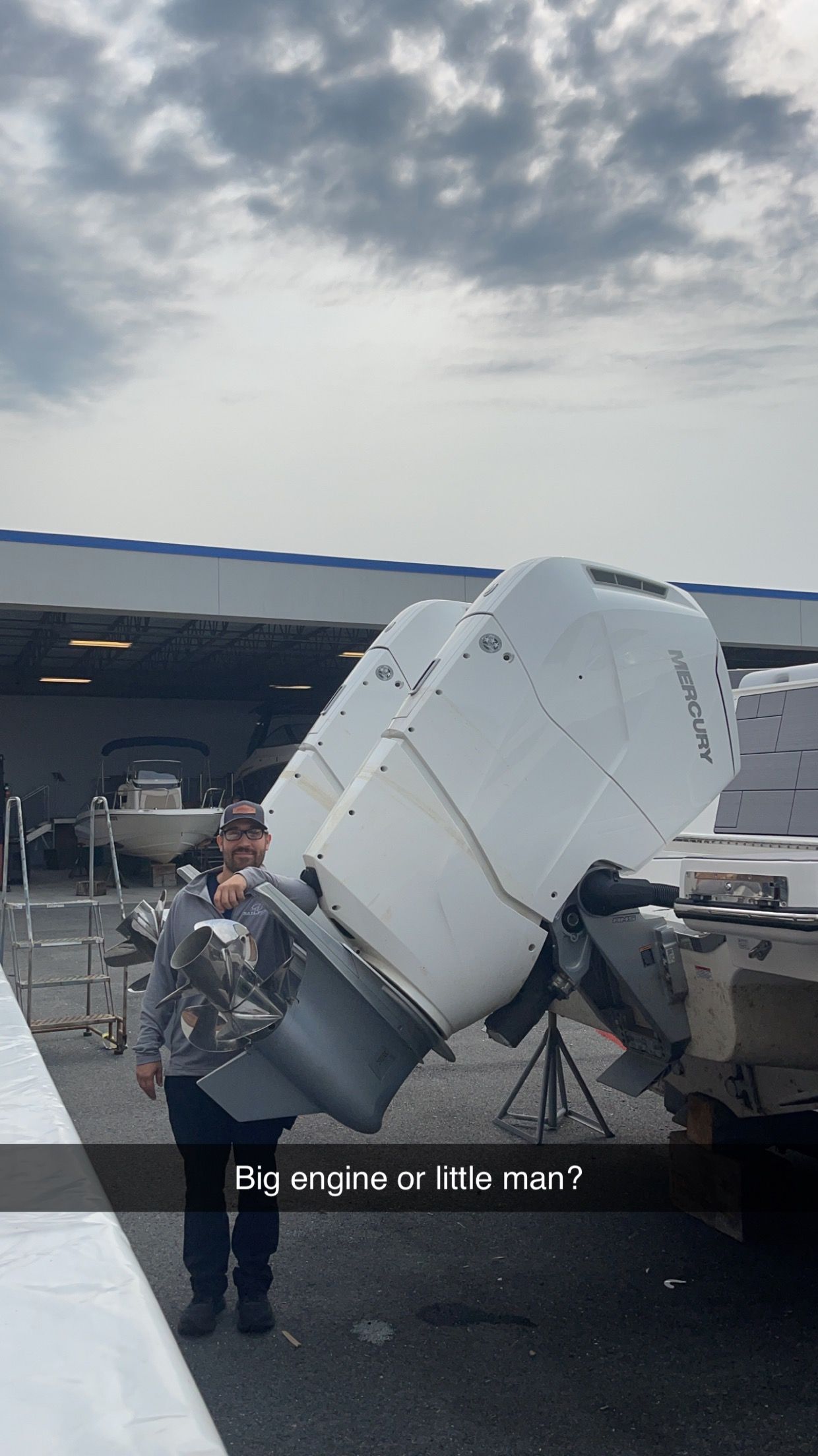 A person stands next to two large, white boat outboard motors, captioned 