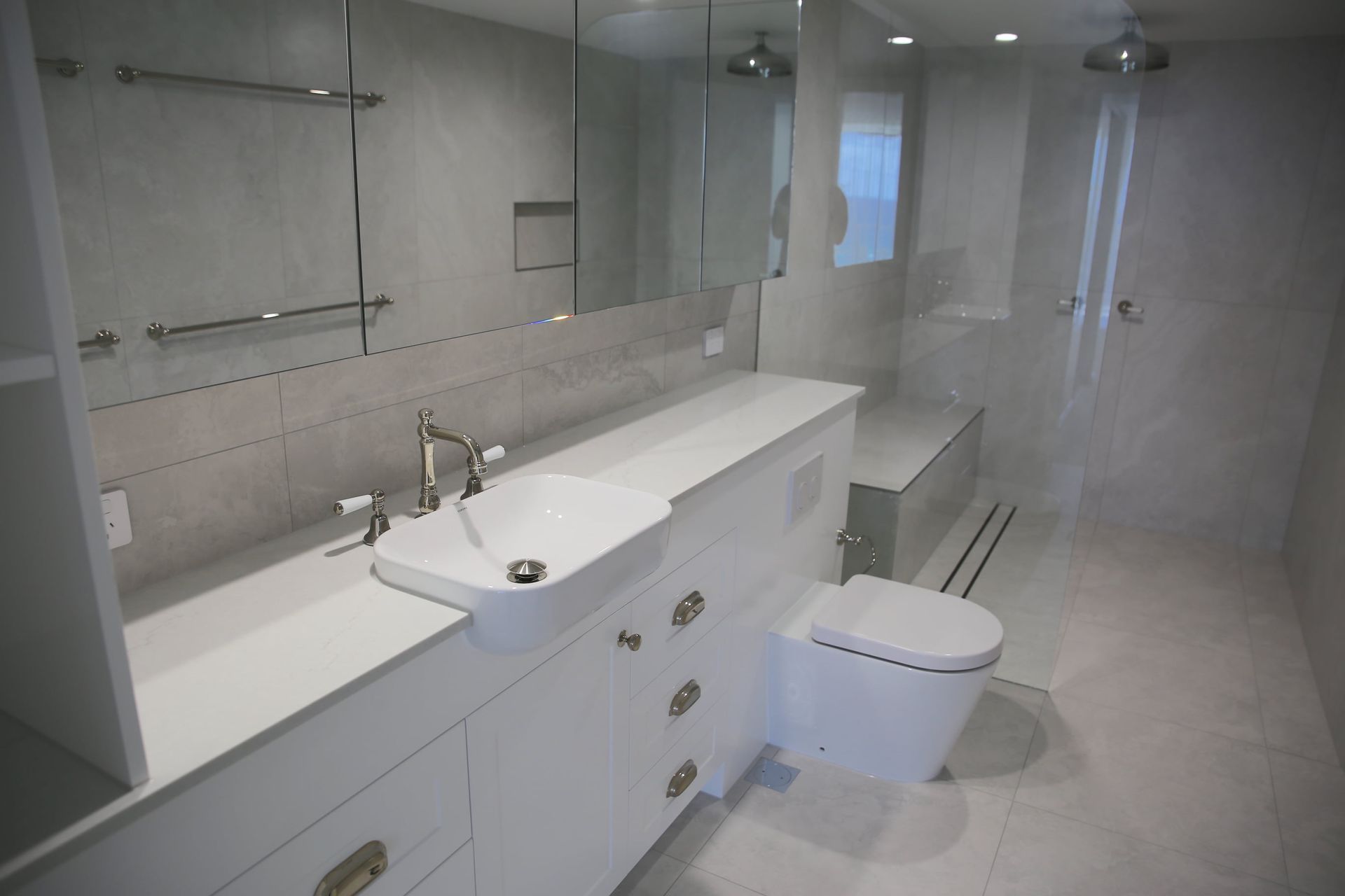 Modern white bathroom with a sink, toilet, and shower.
