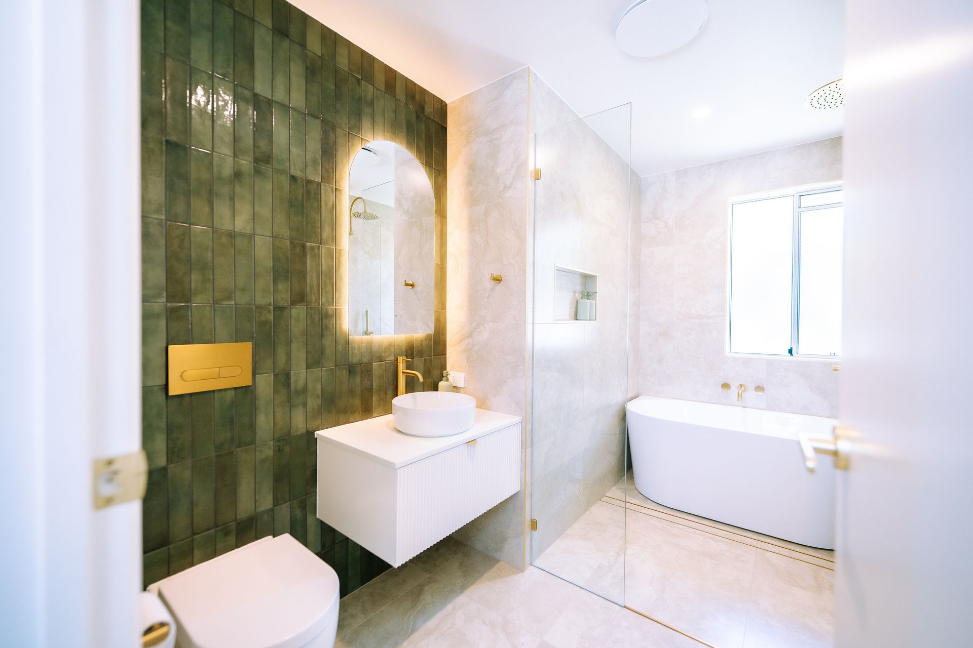 Modern bathroom with green tile accent wall, white vanity and bathtub.